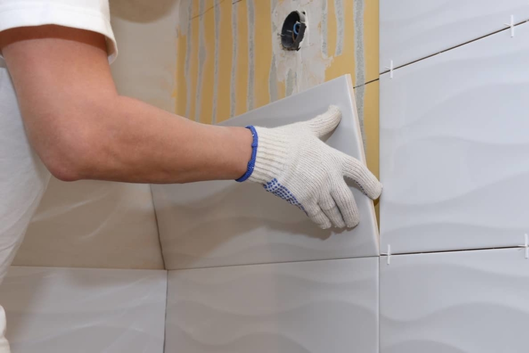 Professional tiler installing a bathroom wall. 