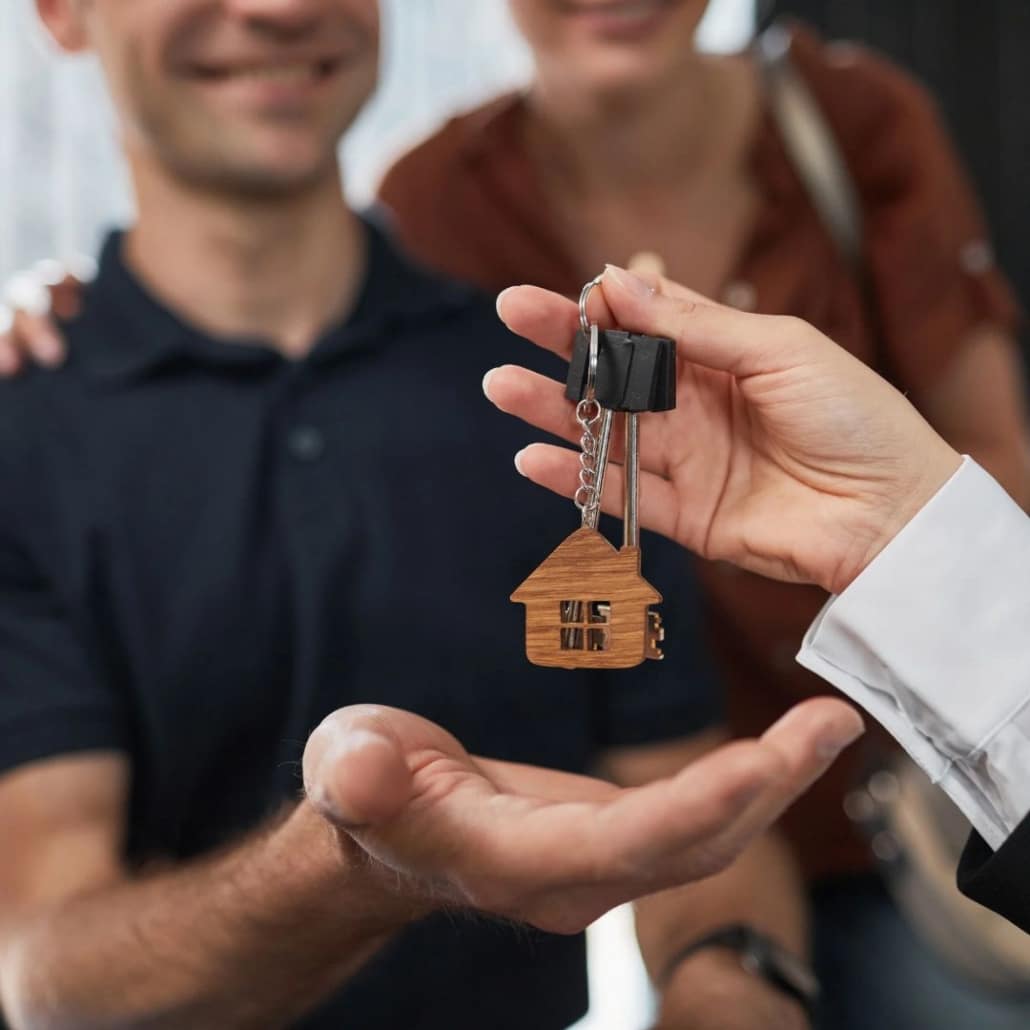 Real estate agent handing house keys to a home buyer, illustrating an article about who pays home inspection buyer or seller.