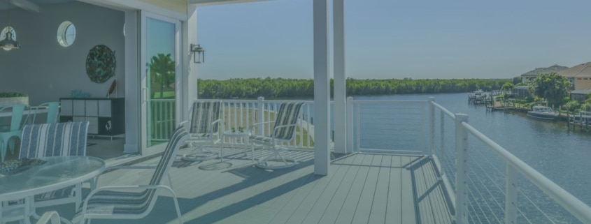 Elevated covered patio deck with lounge chairs and white railings overlooking a scenic waterfront view.